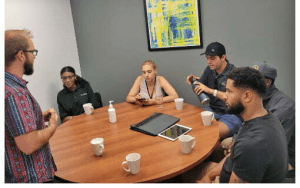 Our sales agents having a team meeting in a boardroom. Five people are sitting while one leader is standing and presenting.